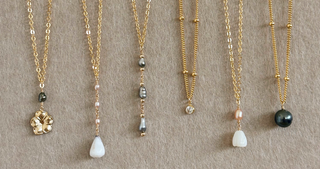 Set of gold necklaces with various pendants on a textured beige background